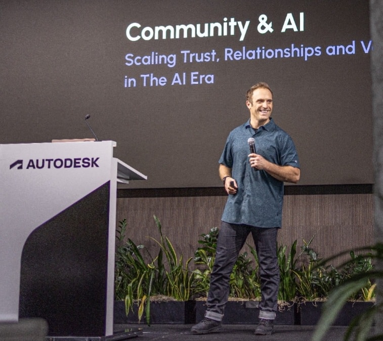 Chris Catania speaking beside a Community & AI presentation at an Autodesk podium